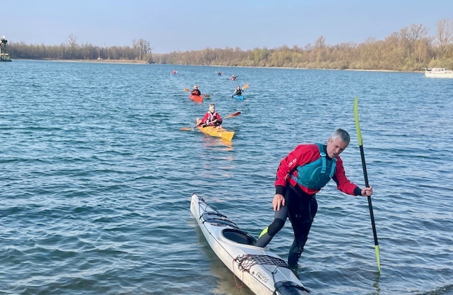 Die Paddelgruppe kommt über den See ans Ziel gepaddelt - der erste Paddler vorne steigt gerade schon aus